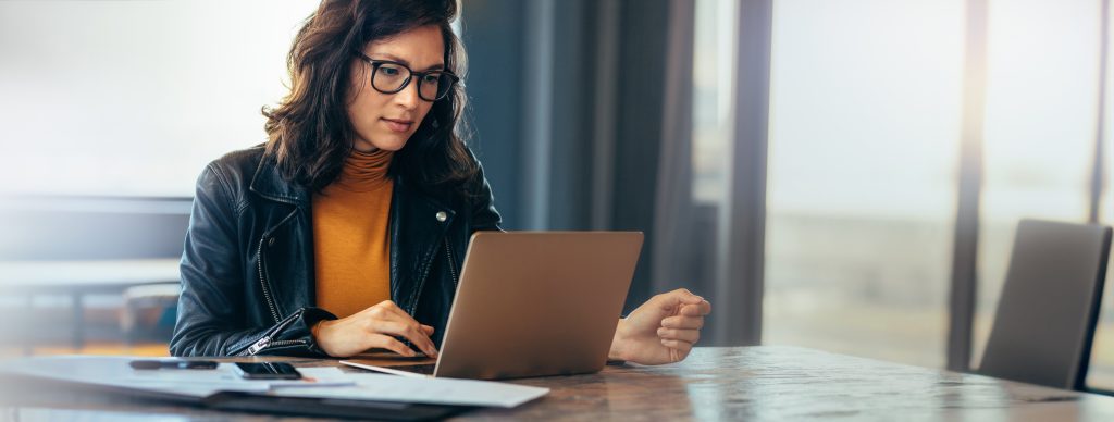 Professional woman sitting at a table working on a laptop