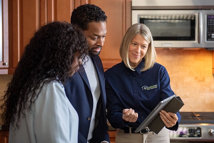Professional home inspector reviewing inspection report with clients in a modern kitchen during a home evaluation.