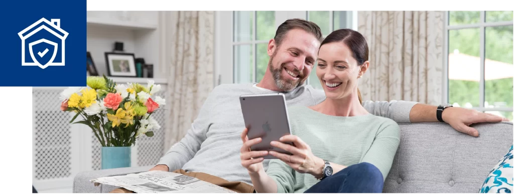 Smiling couple on a sofa reading a tablet together at home.