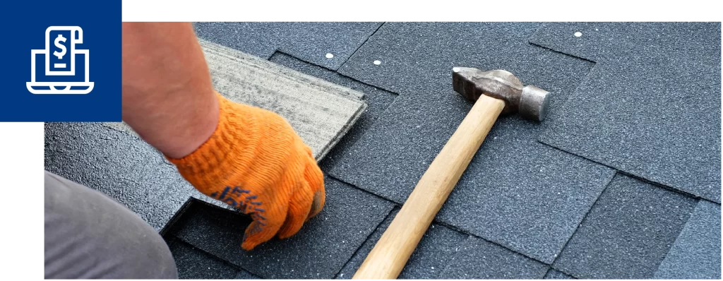 Worker repairing asphalt roof shingles with a hammer during roofing maintenance